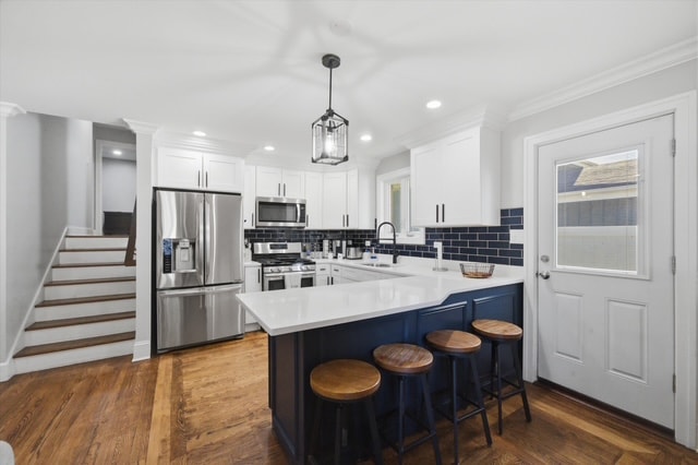 Kitchen with navy island, white cabinets and stainless appliances